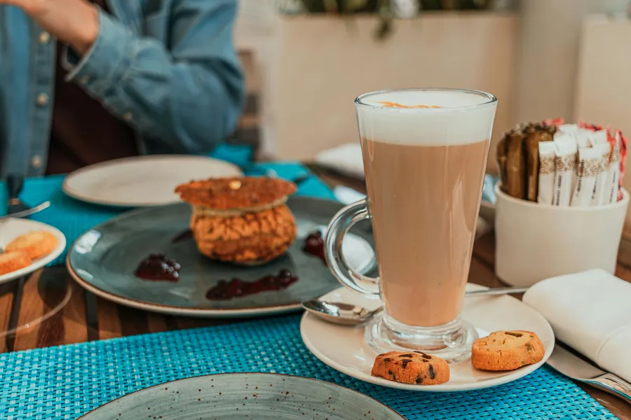 Latte macchiato und Gebäck auf einem Tisch mit türkisem Platzset