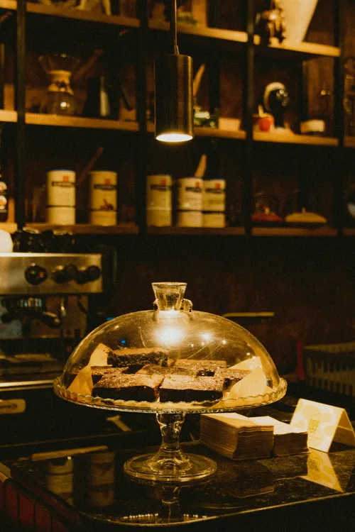 Kuchen unter einer Glashaube auf der Theke, dahinter Regale